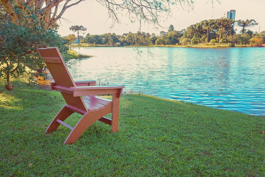 Cadeira Adirondak posta no gramado com vista para um lindo lago em uma tarde ensolarada